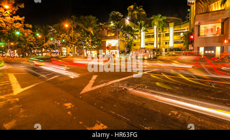 HONOLULU, OAHU, HAWAII, USA - 21. August 2016: Autos überqueren die Kalakaua Ave und Seaside Ave Kreuzung in Bewegung verwischen mit Straßen-leuchten. Urban nahe Stockfoto