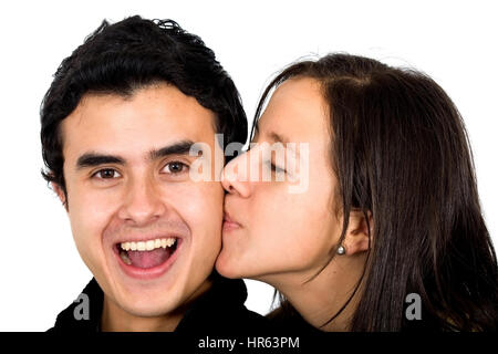 lässige paar suchen glücklich wo der Freund einen Kuss von seiner Freundin - Lächeln auf den Lippen und isoliert auf einem weißen Hintergrund empfängt Stockfoto