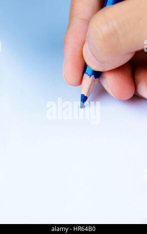 Hand, die eine blaue Farbe Bleistiftzeichnung auf einem weißen Blatt Papier Stockfoto