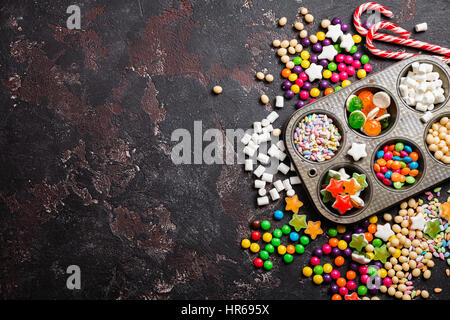 Bunte Bonbons und Lutscher in schwarzem Stein. Draufsicht mit Textfreiraum Stockfoto
