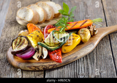 Vegane Küche: Gegrilltes Gemüse auf einem Holzbrett serviert mit italienischen Ciabatta Brot Stockfoto