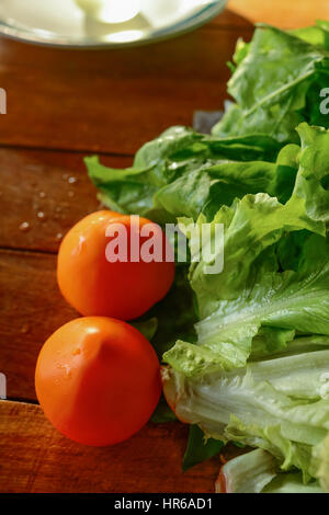 Rote Tomaten und grünem Salat auf einem Holztisch. Nützliche Gemüse. Gesunde Lebensweise. Selektiven Fokus. Stockfoto