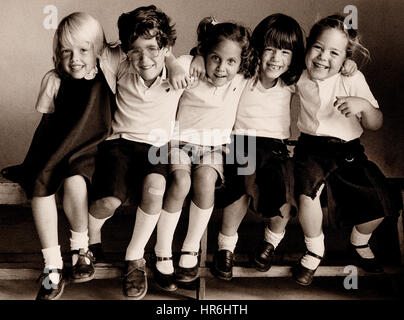 RETRO BILDUNG JUNIOR SCHOOL HAPPY NATÜRLICHE KIND GRUPPE 5-7 Jahre 3 Mädchen und 1 Junge lächelnd saß auf der Bank, für Kodak Kunst von 35 mm Buch gemacht. Bild B&W Kodak Tri-X film Studie der Grundschüler zusammen sitzt auf der Bank in natürlichem Licht, genießen, zusammen zu sein und eine informelle Schule Foto genommen.. Ian Shaw Kodak Fotograf Stockfoto