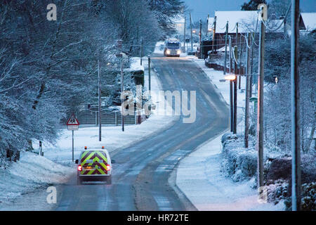 Verkehr, Reisen entlang einer Straße durch das Dorf Rhosesmor bei schweren Frühlingsschnee in Flintshire, Nordwales Stockfoto