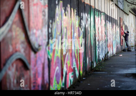 Belfast, Nordirland. 27. Februar 2017. Graffiti-Künstler sprüht auf eine Friedensmauer in einem pro-britische Teil von Belfast, Nordirland, 27. Februar 2017. Mächtigen Mauern und Metallzäune schlängeln sich durch Belfast, teils über zwölf Meter hoch und von Stacheldraht gekrönt. Sie trennen Wohngebiete voneinander, in gerader Linie oder in einem Zick-Zack-Kurs. Die Katholiken Leben auf der einen Seite, die Protestanten auf der anderen. Foto: Mariusz Smiejek/Dpa/Alamy Live News Stockfoto