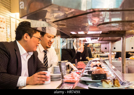 Ein Sushi-Restaurant, wo das Essen auf einem Sushi-Zug in Shinjuku, Tokio, Japan präsentiert wird. Stockfoto