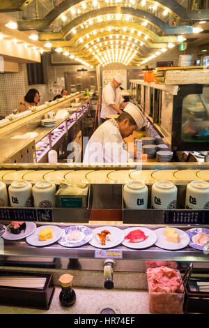 Ein Sushi-Restaurant, wo das Essen auf einem Sushi-Zug in Shinjuku, Tokio, Japan präsentiert wird. Stockfoto