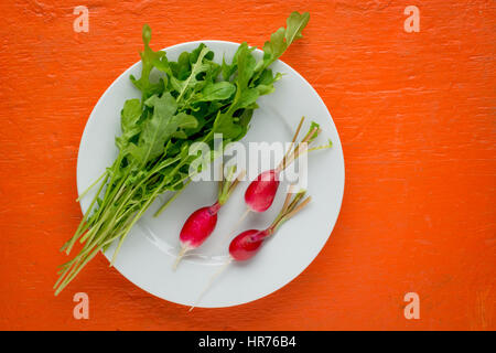 Teller mit frischen gesunden Salat auf orange Tisch. Gesunde Ernährung Draufsicht. Stockfoto