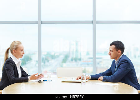 Blick auf zwei Geschäftsleute, Mann und Frau, Vertretung von Seiten des Vertrages, einander gegenüber sitzen am Tisch diskutieren viel während der Meet-Profil Stockfoto