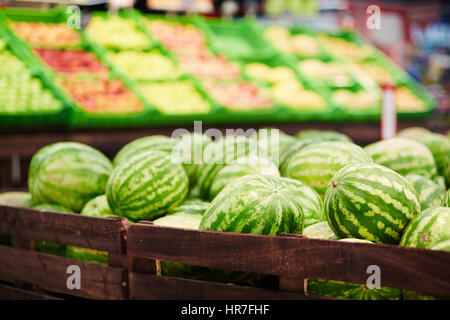 Haufen von frische reife Wassermelonen in Holzkisten in Obst und Gemüseabteilung des Supermarktes liegen Stockfoto