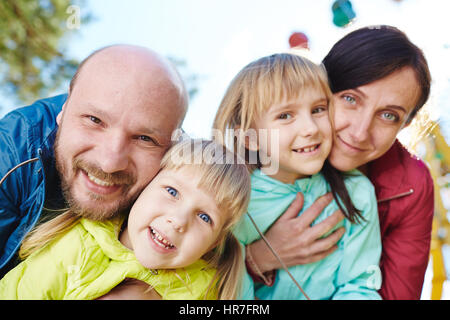 Freudige vierköpfige Familie posieren für Fotografie und dabei Spaß im sonnigen Frühlingspark Stockfoto