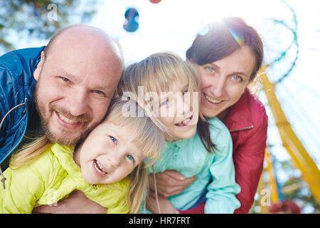 Taille-Up Portrait von glückliche Familie von vier die Freude an Ausgaben sonnigen Tag zusammen in Kirmes, Blendenfleck Stockfoto