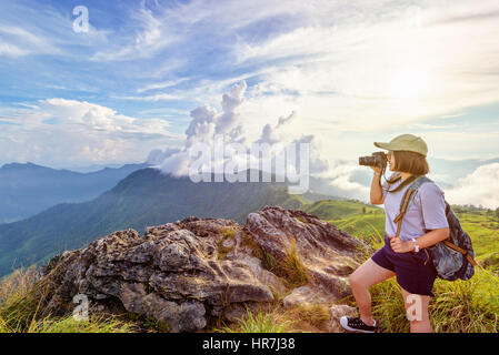 Teen Asiatin Wanderer tragen, Kappe und Brillen mit glücklich halten Dslr Kamera schießen Foto Natur im Winter am Spitzberg bei Sonnenuntergang Stockfoto