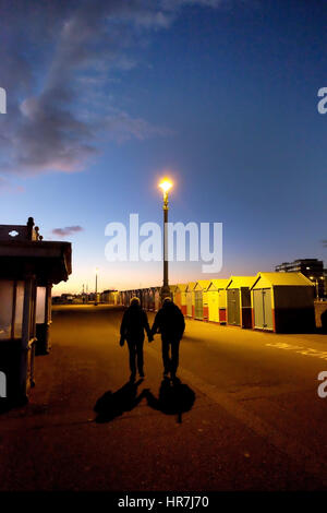 Brighton Seafront, weiße "kein Radfahren" auf dem Boden im Vordergrund, eine Reihe von bunten Strandhäuschen, Straßenlaterne beleuchtet in der Nacht, blauer Himmel schriftlich melden, Stockfoto