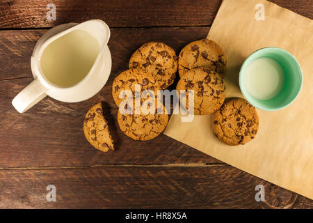 Eine obenliegende Foto Schokolade chips Cookies auf Backpapier, mit einem Glas und einem Glas Milch und Textfreiraum Stockfoto