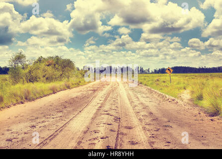 Gelbes Schild mit sandigen Boden Straße in Landschaft umdrehen Sie links Balck. Filmische Straße Landschaft. Argentinien. Südamerika Stockfoto