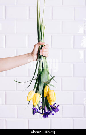 Weibliche Hand wirft ein Bouquet von gelben und violetten Blüten vertikale Rahmung Stockfoto