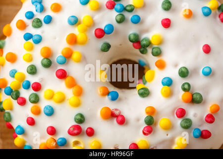 Nahaufnahme von Donuts mit weißem Zuckerguss und bunten knusprig Kugeln Stockfoto