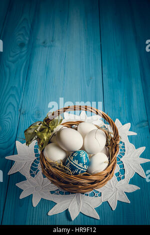 Gruppe von Eiern im Weidenkorb auf der blauen hölzernen Oberfläche. Ostern-Konzept. Stockfoto