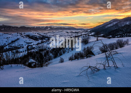 Schönen warmen Winter Sonnenaufgang auf bewölkten Morgen mit Schnee bedeckten Felder in der Nähe des ländlichen Gebiet der Karpaten. Stockfoto