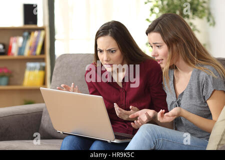Zwei Freunde, die Medieninhalte auf Linie sitzen auf einem Sofa im Wohnzimmer zu Hause beobachten verwechselt Stockfoto