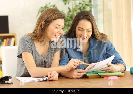 Zwei Schüler Hausaufgaben zusammen und helfen einander sitzen in einer Tabelle zu Hause mit einem heimeligen Hintergrund Stockfoto