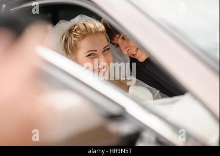 glückliche Braut und Bräutigam in das Hochzeitsauto Stockfoto