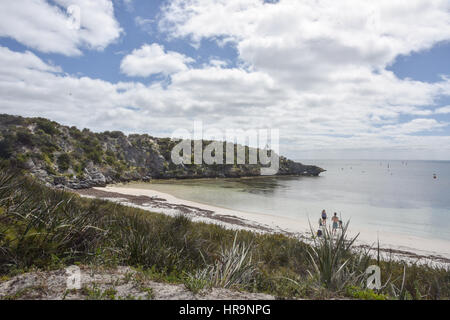 Zerklüfteten Kalkstein mit zu Tage tretenden vegetierten Dünen und ruhiger indischen Ozean Wasser unter blauem Himmel mit Wolken auf Rottnest Island in Western Australia. Stockfoto