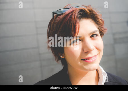 junge authentische Business-Frau lächelnd auf moderne Wand Hintergrund Stockfoto