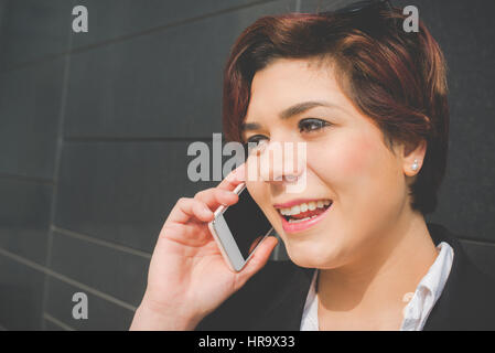 authentische Jungunternehmen Frau Gespräche über ihr Smartphone im Bankenviertel für Geschäftsreise Stockfoto