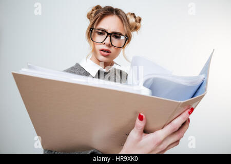 Ernst stirnrunzelnd junge Frau in Gläsern Lesen von Dokumenten im Ordner "" Stockfoto