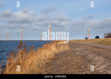 Straße auf der Insel Flevoland in der Nähe von Almere mit Windkraftanlagen und blauer Himmel mit Wolken in den Niederlanden Stockfoto