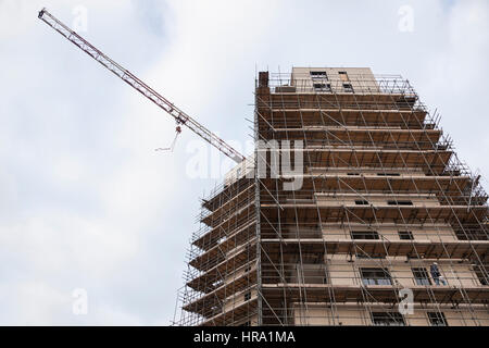 Gerüst auf der Baustelle des neuen Appartementhaus und Kran gegen Himmel Stockfoto