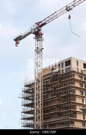 Gerüst auf der Baustelle des neuen Appartementhaus und Kran gegen Himmel Stockfoto