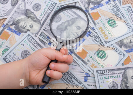 Lupe wird über die Banknote Bündel von US-Dollar gehalten. Stockfoto