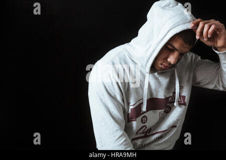 Traurig enttäuscht afroamerikanischen jungen Mann in Hoodie stehen und denken über schwarzen Hintergrund Stockfoto