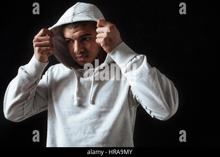 Traurige frustrierte afroamerikanische jungen Mann tragen Hoodie auf schwarzem Hintergrund Stockfoto