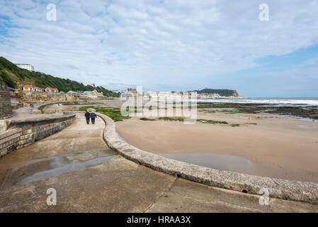 Paar zu Fuß entlang der Promenade nach Scarborough ein beliebter Badeort in North Yorkshire, England. Stockfoto