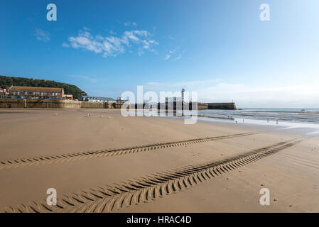 Spuren im Sand neben Scarborough Hafen eine Stadt am Meer an der Ostküste von England. Stockfoto