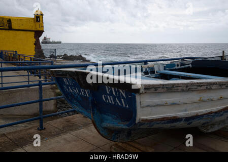 Hölzernes Fischerboot an alte Festung und Frachter in den Hintergrund, Funchal, Madeira, Portugal Stockfoto