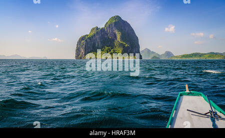 Banca Boot nähert sich riesig Rocky Island am windigen Tag, El Nido, Palawan, Philippinen Stockfoto