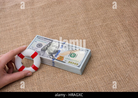 Rettungsring in der Hand über die Banknote Bündel von US-dollar Stockfoto