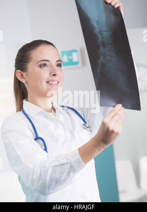 Ärztin, Röntgenaufnahme überprüfen und lächelnd Stockfoto