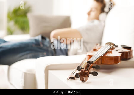 Violine-Nahaufnahme mit Mann, entspannend und anhören von Musik im Hintergrund. Stockfoto