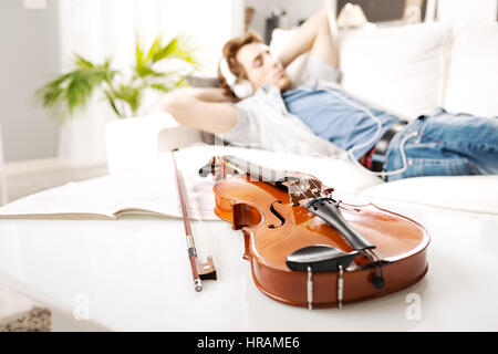 Violine-Nahaufnahme mit Mann, entspannend und anhören von Musik im Hintergrund. Stockfoto