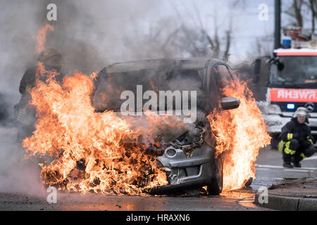 Düsseldorf, Deutschland. 28. Februar 2017. Ein Feuerwehrmann versucht, ein Auto Feuer in Düsseldorf, Deutschland, 28. Februar 2017 löschen. Der Fahrer des Wagens wurde nicht verletzt. Die Ursache des Feuers ist noch unbestimmt. Foto: Federico Gambarini/Dpa/Alamy Live News Stockfoto