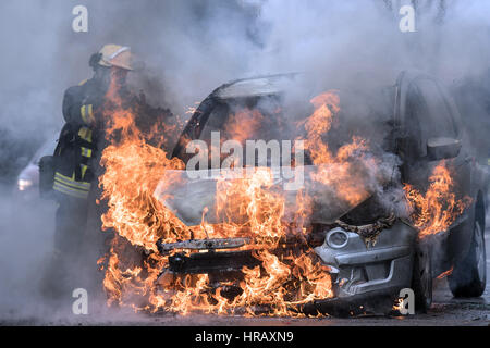 Düsseldorf, Deutschland. 28. Februar 2017. Ein Feuerwehrmann versucht, ein Auto Feuer in Düsseldorf, Deutschland, 28. Februar 2017 löschen. Der Fahrer des Wagens wurde nicht verletzt. Die Ursache des Feuers ist noch unbestimmt. Foto: Federico Gambarini/Dpa/Alamy Live News Stockfoto