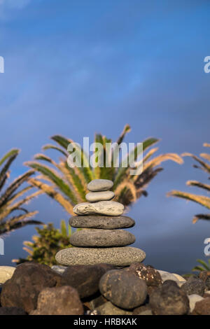 Steinhaufen, Cairn, am Kiesstrand mit Palmen Bäume in den späten Abend Licht, Teneriffa, Kanarische Inseln, Spanien Stockfoto