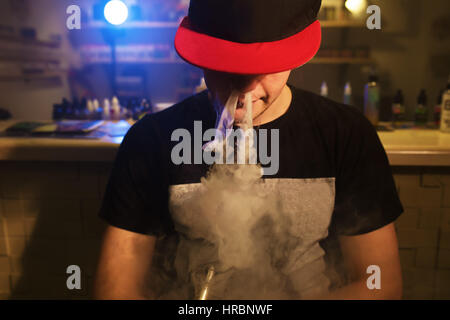 dampfen Mann hält eine mod. Eine Wolke aus Dampf. Schwarzer Hintergrund. Stockfoto