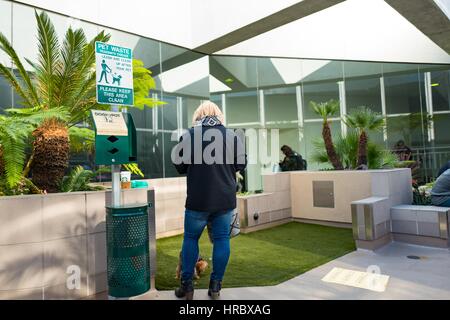 Eine Frau geht mit ihrem Hund in eine neue Outdoor-Tierhilfezone im "sozialen Bereich" von Terminal 2 am Los Angeles International Airport (LAX), Los Angeles, Kalifornien, 22. November 2016. LAX ist einer der wenigen US-Flughäfen, an denen sich ein Tierschutz-Bereich im „sicheren Bereich“ hinter den TSA-Sicherheitskontrollen befindet, sodass Reisende ihre Haustiere unmittelbar vor dem Abflug gehen können. Stockfoto